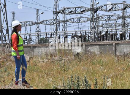 (190605) -- HOMS, 5 giugno 2019 -- Una lavoratrice elettrica si vede dopo aver riparato una linea elettrica ad alta tensione nella provincia di Homs, Siria centrale, il 30 maggio 2019. Mentre la guerra in Siria scoppiava, le donne siriane cominciarono a impegnarsi in più posti di lavoro rispetto al normale lavoro d'ufficio e a crescere bambini, dato che un gran numero di uomini si erano Uniti all'esercito o avevano lasciato il paese per cercare rifugio. I lavori che le donne del paese svolgono sempre più spesso includono la riparazione di automobili, la guida di autobus o taxi e, cosa più interessante, l'uso di una gru per raggiungere le linee elettriche ad alta tensione e ripararle, nonostante tutte le sfide come la famiglia Foto Stock