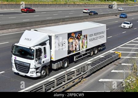 Vista frontale aerea laterale Gist supply chain DAF hgv Truck M&S pubblicità alimentare 100% cacao proveniente in modo responsabile su semirimorchi autostrada M25 Regno Unito Foto Stock