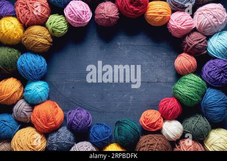 Palline colorate di lana su tavola di legno. Varietà di palle di filato, vista dall'alto. Foto Stock