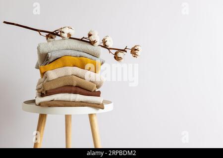 Pila di indumenti ripiegati casual collocati sul tavolo su sfondo bianco. Foto Stock