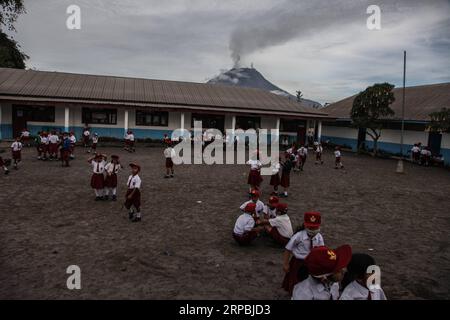 (190610) -- SUMATRA SETTENTRIONALE, 10 giugno 2019 -- gli studenti elementari si riuniscono fuori dalle loro aule dopo l'eruzione del vulcano del Monte Sinabung a Karo, Sumatra settentrionale, Indonesia, 10 giugno 2019. Una colonna di spessa cenere è stata spedita sette km di altezza verso il cielo dal cratere del vulcano del Monte Sinabung nell'isola di Sumatra, nell'Indonesia occidentale, domenica, ha detto l'agenzia nazionale di vulcanologia del paese. ) INDONESIA-SUMATRA SETTENTRIONALE-MONTE SINABUNG-VULCANO ERUZIONE ALBERTXDAMANIK PUBLICATIONXNOTXINXCHN Foto Stock