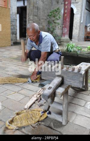 (190614) -- YUDU, 14 giugno 2019 (Xinhua) -- l'artigiano di sandali di paglia Xiao Nandou dimostra il processo di produzione di sandali di paglia nel villaggio di Hanxin, nella contea di Yudu nella provincia del Jiangxi della Cina orientale, 13 giugno 2019. Xiao Nandou, 75 anni, è uno dei pochi artigiani in grado di tessere sandali di paglia nella contea di Yudu. Suo padre, anche lui un artigiano di sandali di paglia, usava tessere 200 paia di sandali di paglia insieme ad altri abitanti del villaggio in pochi giorni affinché i soldati dell'Armata Rossa partissero per la lunga marcia, una manovra militare condotta dai lavoratori cinesi e dall'Armata Rossa contadina dal 1934 al 1936. (Xinhua/Zhou mi) CH Foto Stock