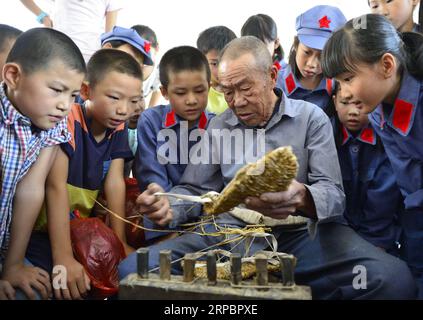 (190614) -- PECHINO, 14 giugno 2019 (Xinhua) -- gli studenti della scuola elementare di Changzhengyuan guardano Chen Luoshou, una progenie del soldato dell'Armata Rossa, per fare sandali di paglia nella contea di Yudu, nella provincia orientale dello Jiangxi della Cina, 31 agosto 2016. (Xinhua/Zhou mi) XINHUA FOTO DEL GIORNO PUBLICATIONxNOTxINxCHN Foto Stock