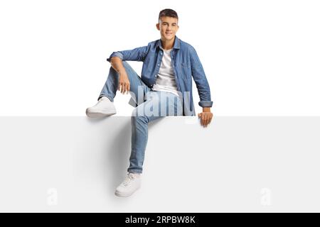 Affascinante ragazzo z di generazione casual seduto su un pannello vuoto isolato su sfondo bianco Foto Stock