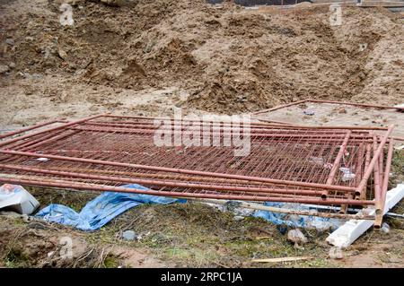 Un disordine in un cantiere con materiali da costruzione sparsi e rifiuti con sporco, scarse precauzioni di sicurezza, condizioni igieniche e ambientali Foto Stock