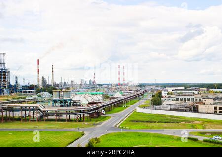 Panorama industriale. Vista panoramica dei tubi tecnologici. Impostazioni impianto. Dai tubi chimici rosso-bianco sta arrivando del fumo. Produzione Foto Stock