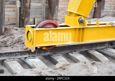 Grande ferro metallo giallo sostiene su rotaie con ruote con un motore a induzione di una grande costruzione stazionaria industriale potente gru a portale di A. Foto Stock