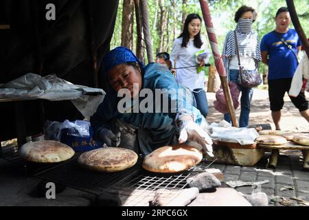 (190625) -- GENHE, 25 giugno 2019 -- i turisti guardano come una donna locale prepara il pane nell'area panoramica della tribù primitiva Olguya nella città di Genhe, nella regione autonoma della Mongolia interna della Cina settentrionale, 25 giugno 2019. La cittadina di Olguya, una destinazione turistica con caratteristiche del gruppo etnico Ewenki conosciuta come l'ultima tribù di caccia in Cina, è testimone di un picco turistico recentemente con l'arrivo dell'estate. Le autorità locali hanno promosso l'industria turistica per aumentare il reddito delle persone del gruppo etnico Ewenki qui dal 2003. ) GRUPPO ETNICO CINESE-INTERNO MONGOLIA-OLGUYA-EWENKI (CN) LIUXLEI PUBLICATIONXNOTXINXCHN Foto Stock