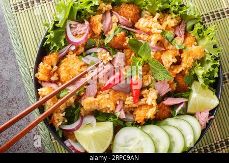 Insalata di palle di riso fritta in Laos con maiale fermentato e primi piani di verdure sul piatto sul tavolo. Vista superiore orizzontale dall'alto Foto Stock