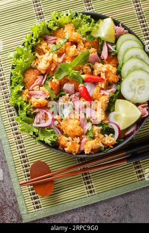 Primo piano dell'insalata di riso croccante del Nam Khao laotiano sul piatto sul tavolo. Vista dall'alto verticale Foto Stock