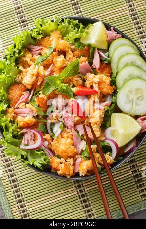 Insalata Khao Pad Naem palla di riso fritta con maiale fermentato, verdure ed erbe per primo piano sul piatto sul tavolo. Vista dall'alto verticale Foto Stock