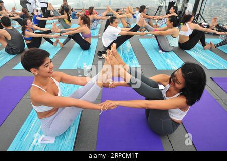 (190708) -- BANGKOK, 8 luglio 2019 -- gli appassionati di yoga assistono alla lezione di yoga all'alba presso la zona sul tetto del Mahanakhon Skywalk a Bangkok, Thailandia, 7 luglio 2019. Il Sunrise Wine yoga combina la gioia di bere vino con le tradizionali pose dello yoga, bilanciando le bevande, sorseggiando e tostando. ) THAILANDIA-BANGKOK-YOGA RachenxSageamsak PUBLICATIONxNOTxINxCHN Foto Stock