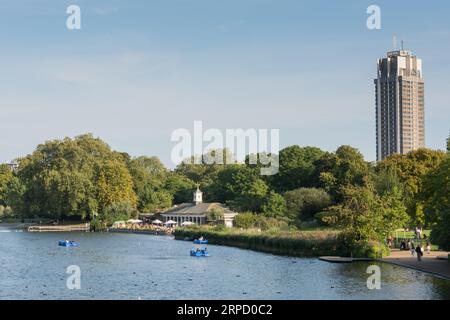 Pedala sul Serpentine nell'Hyde Park di Londra con il Park Lane Hilton sullo sfondo Foto Stock