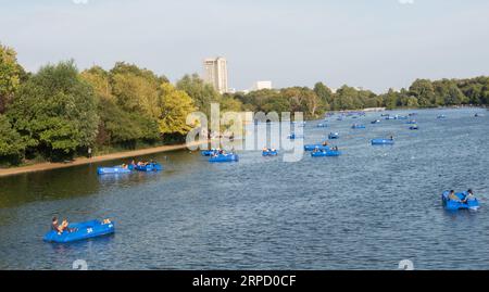 Pedala sul Serpentine nell'Hyde Park di Londra con il Park Lane Hilton sullo sfondo Foto Stock