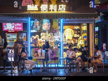 (190717) -- URUMQI, 17 luglio 2019 -- la gente riposa davanti a un minimarket a Urumqi, nella regione autonoma di Xinjiang Uygur della Cina nord-occidentale, 14 luglio 2019. L'economia notturna è in ripresa a Urumqi da luglio. La gente si diverte nelle fresche serate estive facendo shopping e degustando cibo. ) CHINA-XINJIANG-URUMQI-NIGHT-ECONOMY (CN) ZHAOXGE PUBLICATIONXNOTXINXCHN Foto Stock