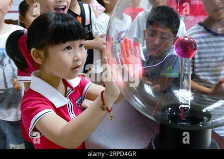 (190722) -- CIXI (ZHEJIANG), 22 luglio 2019 -- Un allievo prova una palla magica al plasma sotto l'istruzione di volontari nella città di Cixi, nella provincia di Zhejiang nella Cina orientale, 22 luglio 2019. Un centro di volontariato nella città di Cixi ha aperto corsi di scienza per gli alunni locali per aiutarli a imparare le conoscenze scientifiche e arricchire le loro vacanze estive. CHINA-ZHEJIANG-BAMBINI-VACANZE ESTIVE (CN) XUXYU PUBLICATIONXNOTXINXCHN Foto Stock