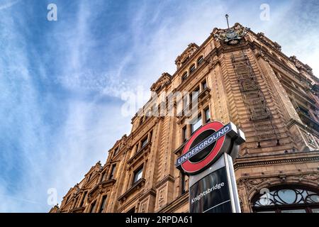 Londra, Regno Unito - 17 aprile 2022: L'insegna della metropolitana di Knightsbridge, fuori dall'ingresso di Harrods, in Brompton Road, Londra. Giorno primaverile con il blu Foto Stock