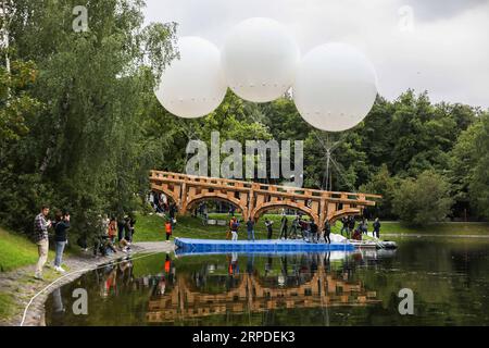 (190801) -- MOSCA, 1 agosto 2019 (Xinhua) -- i volontari sollevano un ponte di cartone e nastro adesivo nel parco Ostankino a Mosca, in Russia, il 1 agosto 2019. Un ponte volante lungo 18 metri realizzato in cartone e nastro per condotti è stato assemblato e installato giovedì nel parco Ostankino di Mosca. Il ponte fu sollevato in aria con l'aiuto di tre palloncini riempiti di elio. (Foto di Maxim Chernavsky/Xinhua) RUSSIA-MOSCA-FLYING BRIDGE PUBLICATIONxNOTxINxCHN Foto Stock