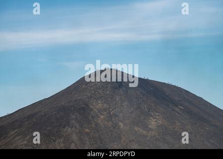 Vista ravvicinata delle persone sulla cima della collina di Litli-Hrútur che osservano la fessura durante l'eruzione del 2023 vicino al monte Fagradalsfjall, vulcano islandese Foto Stock