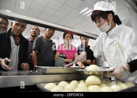 (190812) -- SHOUGUANG, 12 agosto 2019 -- la gente prende pasti in una scuola media, che ora serve come sito di trasferimento, a Shouguang, nella provincia di Shandong, nella Cina orientale, 12 agosto 2019. Circa 93.000 residenti locali sono stati trasferiti quando il tifone Lekima ha causato il caos in alcune parti di Shouguang. CHINA-SHANDONG-TYPHOON-LEKIMA-RELOCATION (CN) GUOXXULEI PUBLICATIONXNOTXINXCHN Foto Stock