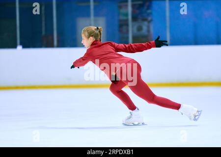 Ragazza adolescente, atleta motivata di pattinaggio artistico in movimento, allenarsi, fare esercizi sull'arena di pattinaggio sul ghiaccio. Educazione sportiva Foto Stock