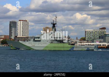 Passando blocchi di appartamenti costieri mentre naviga verso il suo ormeggio portuale: La HMS Tyne è una nave di pattugliamento offshore classe fiume della Royal Navy, e parte dello squadrone di protezione della pesca che protegge le acque intorno al Regno Unito. Foto Stock