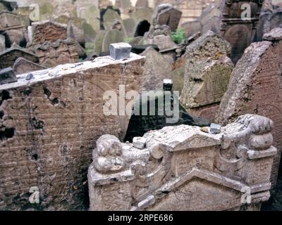 PRAGA, REPUBBLICA CECA - 3 SETTEMBRE 2023: Una singola lapide con incisioni di lettere ebraiche, scura con età e muschio, è affollata da lapidi più leggere. Foto Stock