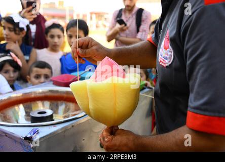 (190821) -- GAZA, 21 agosto 2019 (Xinhua) -- Mohammed al-Wakeel, un palestinese di 33 anni che è bravo a progettare caramelle di cotone in varie forme e colori, produce caramelle di cotone in un parco nella città di Gaza, 19 agosto 2019. (Str/Xinhua) MIDEAST-GAZA-DAILY LIFE-COTTON CANDY PUBLICATIONxNOTxINxCHN Foto Stock