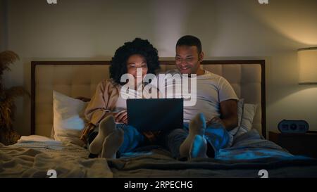 Coppia afro-americana famiglia uomo e donna a letto notte casa notte notte notte notte notte notte notte notte notte notte notte notte notte notte notte notte guardare laptop tv film guardare film rilassante romantico amore data Foto Stock