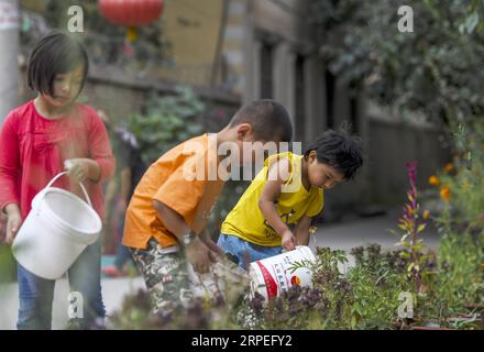 (190828) -- KASHGAR, ago. 28, 2019 -- bambini fiori d'acqua in un vicolo al villaggio di Qianjin a Kashgar, regione autonoma di Xinjiang Uygur, nella Cina nordoccidentale, 18 agosto 2019. Abitazioni circondate da una fioritura profumata in profusione, case ben organizzate e vicoli dall'aspetto pulito, alberi vari che fiancheggiano le strade dove i bambini si divertono, la scena pastorale può essere vista ovunque nel villaggio di Qianjin. La bellezza idilliaca del villaggio di Qianjin deriva dalla sua fioritura economica, in cui Salima Sultan è un pioniere. Salima, un abitante di 60 anni, sviluppò la predilezione dei fiori da allora Foto Stock