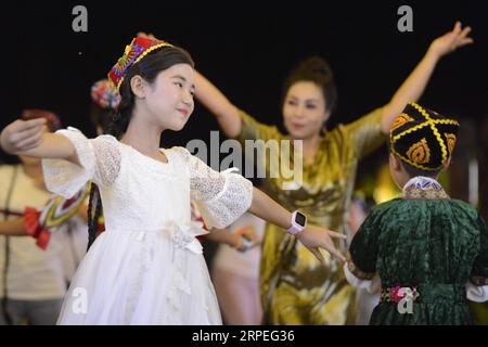 (190828) -- URUMQI, 28 agosto 2019 -- la gente danza in un mercato notturno a Turpan, nella regione autonoma di Xinjiang Uygur della Cina nordoccidentale, 19 luglio 2019. Un numero crescente di residenti locali sta facendo soldi dall'attuale boom turistico nello Xinjiang. Oltre 32.000 persone sono state impiegate nel settore del turismo nella prima metà del 2019. ) CHINA-XINJIANG-ECONOMIA-TURISMO-OCCUPAZIONE (CN) DINGXLEI PUBLICATIONXNOTXINXCHN Foto Stock