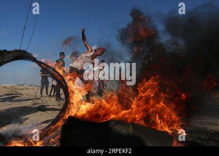 (190830) - PALESTINA, 30 agosto 2019 - Un manifestante palestinese usa una fionda per lanciare pietre contro le truppe israeliane durante gli scontri con le truppe israeliane sul confine tra Gaza e Israele, a est della città meridionale di Khan Younis, 30 agosto 2019. Almeno 54 palestinesi sono rimasti feriti venerdì, durante gli scontri con soldati israeliani nella Striscia di Gaza orientale, vicino al confine con Israele, hanno detto i medici. Stringer) MIDEAST-GAZA-CLASHES guoyu PUBLICATIONxNOTxINxCHN Foto Stock