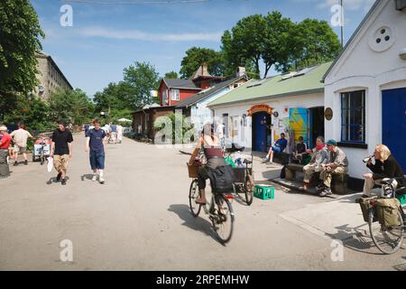 COPENHAGEN, DANIMARCA - 18 giugno 2006. Donna in bicicletta attraverso Freetown Christiania, un comune intenzionale e una grande attrazione turistica a Copenhagen Denm Foto Stock