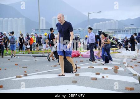 (190901) -- HONG KONG , 1 settembre 2019 -- i passeggeri superano le barriere e raggiungono a piedi l'aeroporto mentre i manifestanti radicali bloccano le strade fuori dall'aeroporto internazionale di Hong Kong, nel sud della Cina, 1 settembre 2019. Un grande gruppo di manifestanti radicali ha accusato linee di cordone di sicurezza, strutture danneggiate e ha interrotto le operazioni dell'aeroporto internazionale di Hong Kong domenica. I manifestanti hanno iniziato a riunirsi alle fermate degli autobus del terminal dell'aeroporto alle 13:00, ora locale. Verso le 14:00, i manifestanti radicali hanno iniziato a caricare barriere piene d'acqua, raggi laser puntati all'aeroporto auth Foto Stock