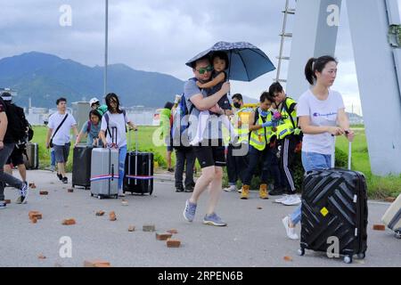 (190901) -- HONG KONG , 1 settembre 2019 -- i passeggeri superano le barriere e raggiungono a piedi l'aeroporto mentre i manifestanti radicali bloccano le strade fuori dall'aeroporto internazionale di Hong Kong, nel sud della Cina, 1 settembre 2019. Un grande gruppo di manifestanti radicali ha accusato linee di cordone di sicurezza, strutture danneggiate e ha interrotto le operazioni dell'aeroporto internazionale di Hong Kong domenica. I manifestanti hanno iniziato a riunirsi alle fermate degli autobus del terminal dell'aeroporto alle 13:00, ora locale. Verso le 14:00, i manifestanti radicali hanno iniziato a caricare barriere piene d'acqua, raggi laser puntati all'aeroporto auth Foto Stock