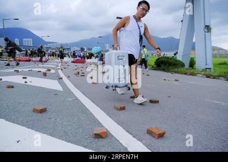 (190901) -- HONG KONG , 1 settembre 2019 -- i passeggeri superano le barriere e raggiungono a piedi l'aeroporto mentre i manifestanti radicali bloccano le strade fuori dall'aeroporto internazionale di Hong Kong, nel sud della Cina, 1 settembre 2019. Un grande gruppo di manifestanti radicali ha accusato linee di cordone di sicurezza, strutture danneggiate e ha interrotto le operazioni dell'aeroporto internazionale di Hong Kong domenica. I manifestanti hanno iniziato a riunirsi alle fermate degli autobus del terminal dell'aeroporto alle 13:00, ora locale. Verso le 14:00, i manifestanti radicali hanno iniziato a caricare barriere piene d'acqua, raggi laser puntati all'aeroporto auth Foto Stock