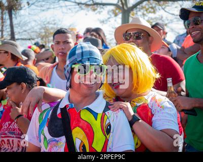 Barranquilla, Atlantico, Colombia - 18 febbraio 2023: Uomo colombiano che indossa una maglietta colorata, occhiali e berretto accanto a una donna che indossa una Yell Foto Stock