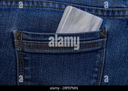 Fazzolettini inseriti nella tasca posteriore dei jeans blu Foto Stock