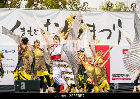 Squadra di danza giapponese di Yosakoi in costumi gialli e neri su un palco all'aperto che balla al festival annuale di Kumamoto Kyusyu Gassai. Foto Stock