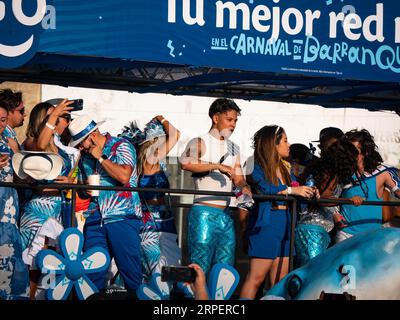 Barranquilla, Atlantico, Colombia - 18 febbraio 2023: Uomini e donne vestite di blu su un galleggiante nella parata di Carnevale saltano a una folla Foto Stock