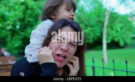 Un ragazzino incauto che soffoca la mamma mentre gioca. Il ragazzo non conosce i limiti del gioco, la madre sconvolta, la vita reale Foto Stock