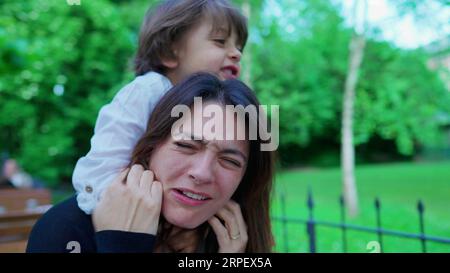 Un ragazzino incauto che soffoca la mamma mentre gioca. Il ragazzo non conosce i limiti del gioco, la madre sconvolta, la vita reale Foto Stock