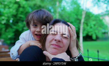 Un ragazzino incauto che soffoca la mamma mentre gioca. Il ragazzo non conosce i limiti del gioco, la madre sconvolta, la vita reale Foto Stock