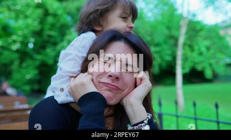 Un ragazzino incauto che soffoca la mamma mentre gioca. Il ragazzo non conosce i limiti del gioco, la madre sconvolta, la vita reale Foto Stock