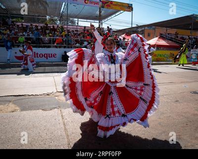 Barranquilla, Colombia - 21 febbraio 2023: Donna colombiana vestita di sorrisi bianchi e rossi al camera Dancing con il costume tradizionale della costa Foto Stock