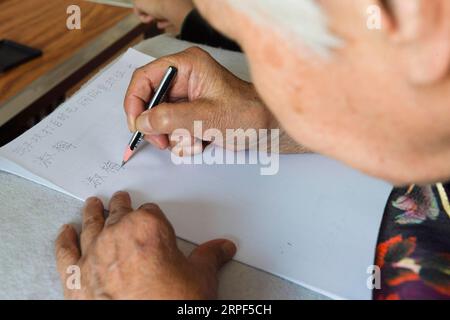 (190913) -- SUIHUA, 13 settembre 2019 -- Jiang Shumei pratica di scrivere il suo nome a casa nel distretto di Beilin della città di Suihua, provincia di Heilongjiang della Cina nord-orientale, 12 settembre 2019. Nato nel 1937, Jiang era analfabeta prima dei 60 anni. Per alleviare la sofferenza di Jiang dopo la morte del marito nel 1996 in un incidente d'auto, sua figlia Zhang Lailing ha insegnato alla donna anziana a leggere e scrivere da allora. Con l'incoraggiamento di sua figlia, Jiang ha cercato di scrivere un libro. Nel 2013 fu pubblicato il primo libro di Jiang. Finora, lo scrittore di 82 anni ha pubblicato cinque libri e ha vinto diversi premi. ) CHINA-HEIL Foto Stock