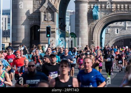 Divertenti corridori che gareggiano nella Big Half, mezza maratona organizzata da London Marathon Events, a partire da Tower Hamlets attraversando il Tower Bridge. Foto Stock