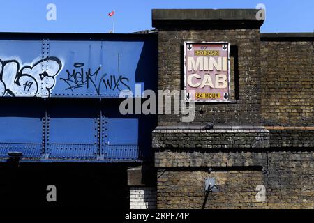 Un vecchio cartello della Mini Cab fissato su un ponte ferroviario, Waterloo, Londra, Regno Unito. 26 maggio 2023 Foto Stock