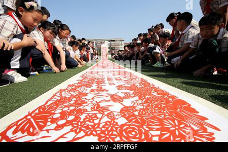 190923 -- ZAOZHUANG, 23 settembre 2019 -- gli studenti vedono un'opera d'arte di taglio della carta a tema raccolto presso la scuola elementare Jianshelu nella città di Zaozhuang, nella provincia orientale dello Shandong della Cina, 23 settembre 2019. Gli agricoltori di tutto il paese celebrano il festival cinese del raccolto degli agricoltori, che cade nell'Equinozio d'autunno, o il 23 settembre di quest'anno. Foto di /Xinhua CHINA-HARVEST FESTIVAL-CELEBRATION CN SunxZhongzhe PUBLICATIONxNOTxINxCHN Foto Stock