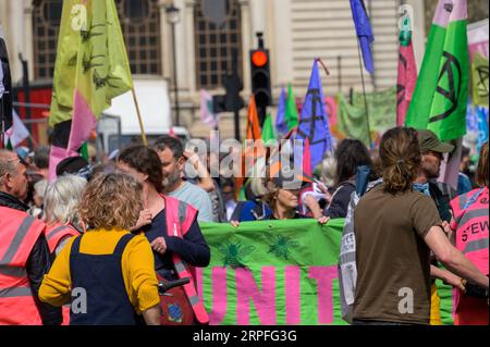 LONDRA - 22 aprile 2023: I sostenitori del clima di Londra: I manifestanti XR si riuniscono in città con colorate bandiere XR sullo sfondo, sottolineando il loro de Foto Stock